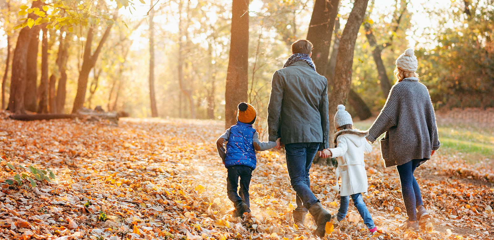 family walking through a forest with falling leaves