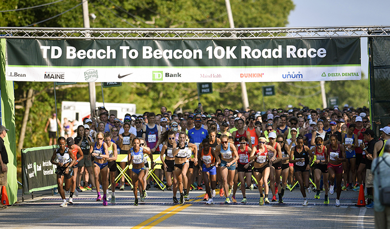 Runners running through the starting line at the TD Beach to Beacon 10K Road Race