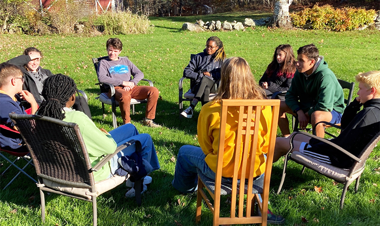 Teenagers sitting outside in chairs in a circle