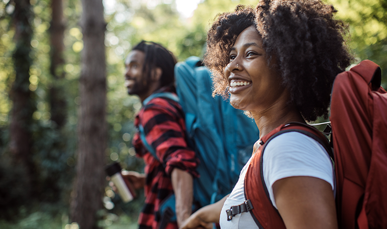 Woman in hiking gear holding hands with a man in hiking gear hiking in the forest